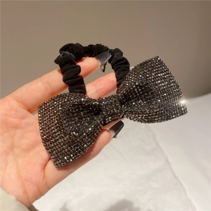 Close-up of sparkling black rhinestone bow hair tie with elastic fabric band