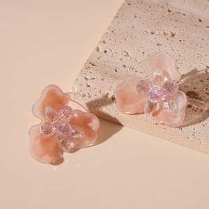 Close-up of pink resin flower earrings with crystal centers on travertine stone