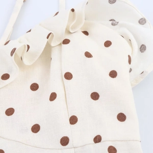Detailed close-up of ruffle collar on beige midi dress with brown polka dot pattern