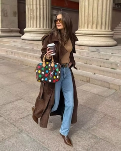 Gros plan d'un trench-coat en daim marron avec un sac à main de créateur à motifs