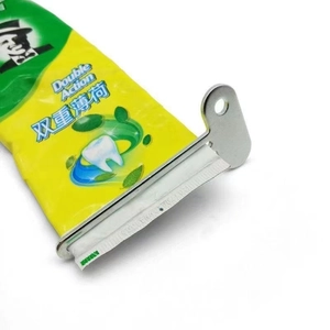 Close-up of the metal toothpaste squeezer rolling a tube to extract contents efficiently