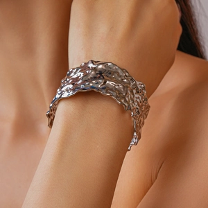 Close-up of a wide silver cuff bracelet featuring liquid lava textured metal on wrist