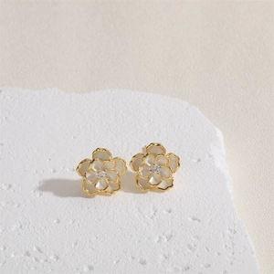 Detailed shot of camellia flower earrings with gold base, white enamel, and zircon