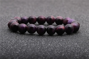 Dettaglio macro di perle in pietra occhio di tigre viola scuro su un bracciale
