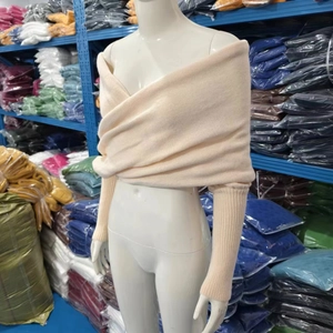 Dettaglio maglione incrociato in maglia beige con polsini a coste e maniche lunghe