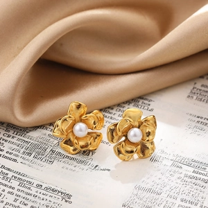 Macro shot of gold floral pearl earrings on silk fabric and vintage paper