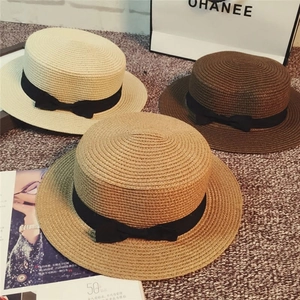 Detailed view of three woven boater hats in beige, khaki and coffee with black grosgrain bows