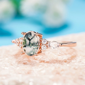 Macro shot of rose gold ring with marquise moss agate and white zircon stones
