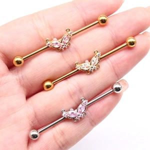 Detail of butterfly industrial barbell earrings with pink zircon held in hand