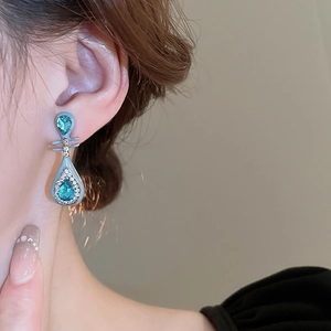 Elegant teardrop lute earrings with blue enamel and sparkling crystals worn by model