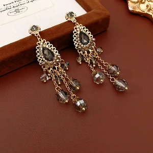 Close-up of bohemian tassel earrings with grey crystals and gold filigree details