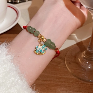 Détail du bracelet en cordon rouge avec pendentif poney, gourde en jade et perles