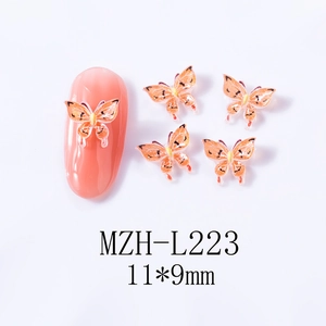 Detailed view of orange butterfly nail charms with black spots on manicured tips
