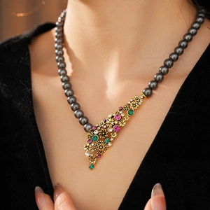 Détail du collier fleur vintage avec perle noire et cristaux multicolores brillants