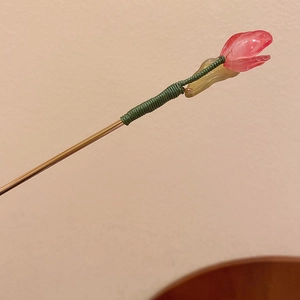 Detail of handcrafted pink flower hairpin with green silk-wrapped stem and gold-toned metal