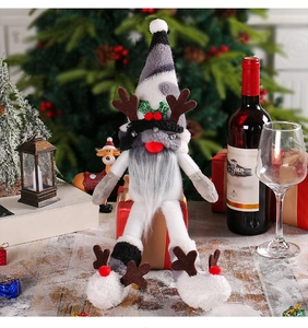 Close-up of a Christmas gnome doll with reindeer antlers sitting on a red gift box