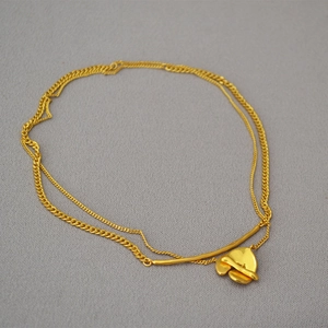 Close-up of a double-layered gold necklace featuring an irregular heart-shaped pendant