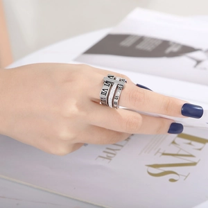 Dettaglio del set di anelli in argento con numeri romani e zirconi su sfondo di rivista moda