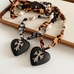 Detail of fabric cross necklace with black heart pendant and leopard print textile strap