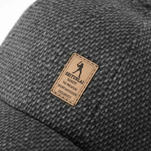 Close-up of gray knit fabric texture and leather logo patch on winter baseball cap