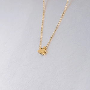 Close-up of golden stainless steel puzzle pendant with mirror finish and slim chain