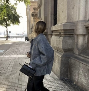 Detailed view of gray wool bomber jacket with stand collar and black leather shoulder bag