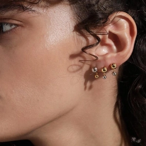 Gros plan de boucles d'oreilles boules bicolores or et argent portées sur le mannequin