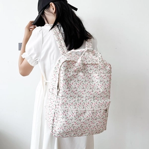 Detailed back view of pink floral backpack with shoulder straps on a white dress model