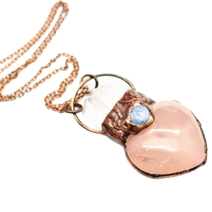 Vintage copper necklace with heart pink crystal pendant and blue accent on white backdrop