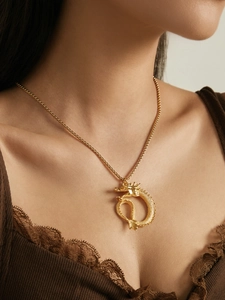 Detailed close-up of a golden dragon pendant necklace worn by a model in dark lace