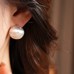 Gros plan d'une boucle d'oreille demi-ronde en métal brossé avec strass étoiles