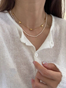 Close-up of double-layer necklace set with golden heart charms and white pearls