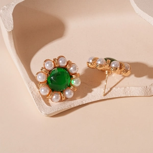 Detailed close-up of vintage flower earrings with green emerald gems and pearls