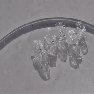 Macro view of jelly nail stickers with 3D white butterfly and rhinestone decorations