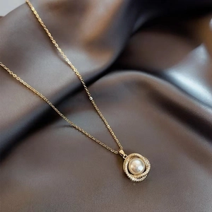 Macro shot of elegant gold necklace with pearl pendant and double rhinestone rings