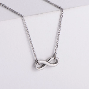 Minimalist silver infinity pendant necklace in polished titanium steel on white stand