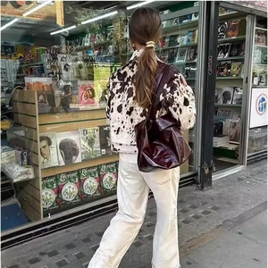Giacca a camicia con stampa mucca e borsa a tracolla bordeaux in un contesto urbano