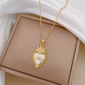 Macro detail of gold crown heart pendant with white enamel and sparkling crystals