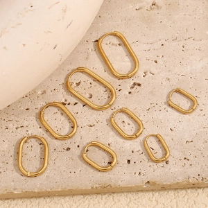 Flat lay of U-shaped gold plated stainless steel hoop earrings in various sizes on stone