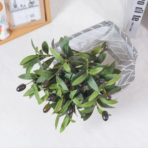 Artificial olive branch with green leaves and black fruit in a grey geometric basket
