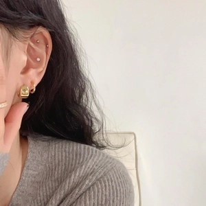 Close-up of gold chunky square hoop and thin gold ring earring on female model ear