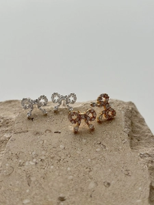Close-up of sparkling bow earrings in gold and silver finish with zircon micro-paving