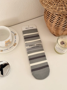 Close-up of gray striped cotton crew socks in branded paper packaging on a table