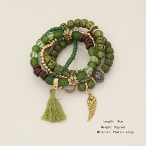 Detail of bohemian multi-layer beaded bracelet with green tassels and golden wing charms