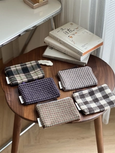 Detailed display of plaid fabric mini pouches with zippers in five assorted color patterns