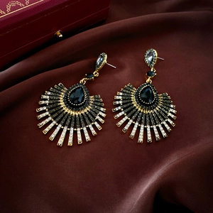 Détail de boucles d'oreilles en éventail avec cristaux noirs sur soie rouge
