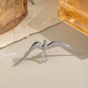 Macro detail of silver swallow bird ring featuring a polished metallic finish on warm background