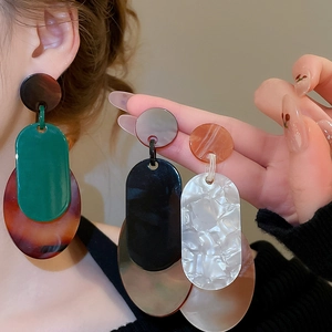 Détail de boucles d'oreilles ovales géométriques en acrylique avec texture marbrée élégante