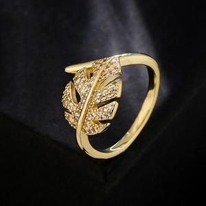 18K gold plated copper leaf ring with white cubic zirconia on a dark textured background