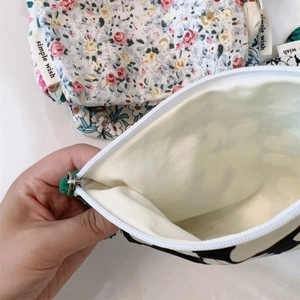 Detail view of cotton floral pouch interior with zipper closure and brand label
